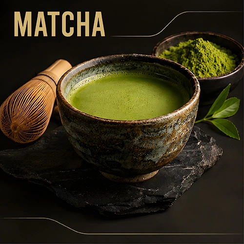 Matcha green tea in a ceramic bowl with a bamboo whisk and matcha powder